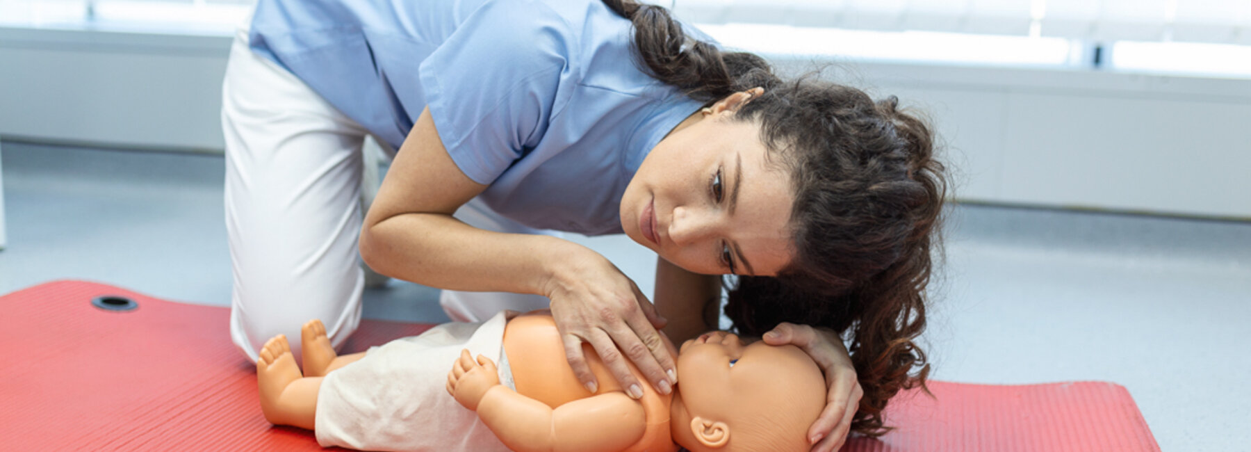 Demonstratie van reanimatie op een babypop tijdens een cursus eerste hulp voor baby's en kinderen.